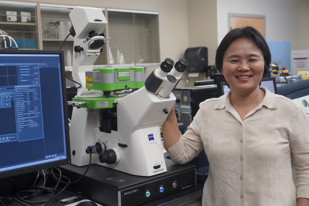 Linxia Gu, biomedical and chemical engineering and sciences and mechanical and civil engineering professor, with the university's new atomic force microscope housed in her Bio-Mechanics Laboratory
