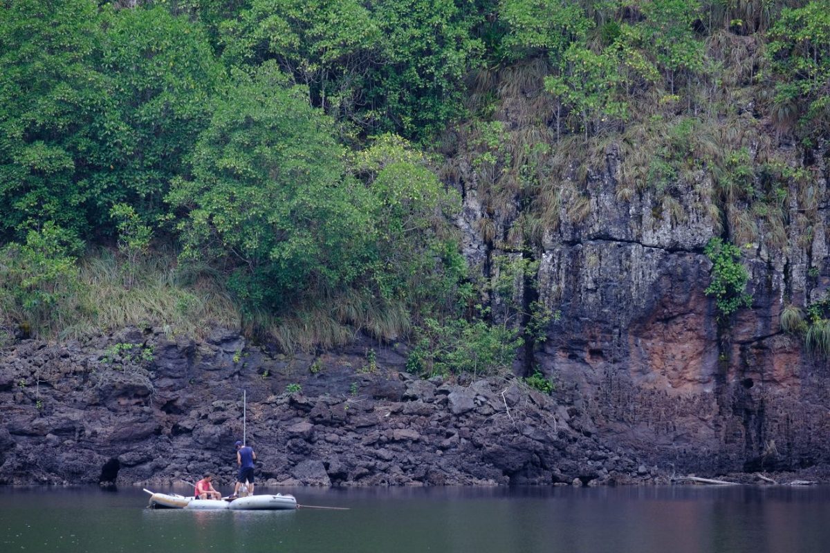 A raft floats on a large lake next to a steep rock wall in Brazil.