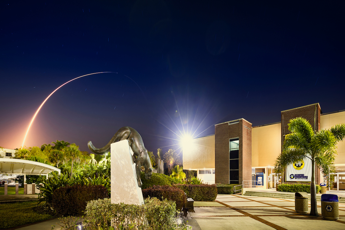 Night sky lit up by a launch over Panther statue in Panther Plaza.