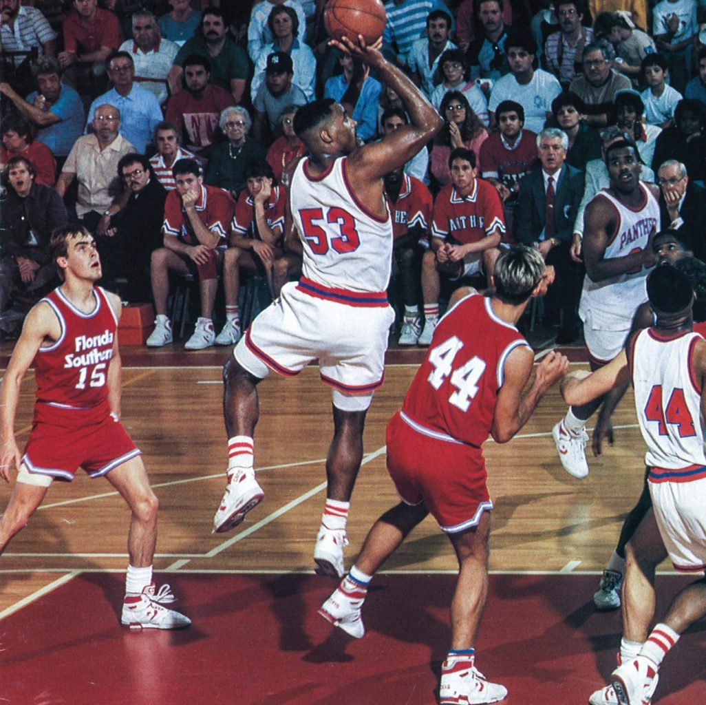 Basketball game, Astley Smith, No. 53, shooting the ball in front of a crowd and among four other players