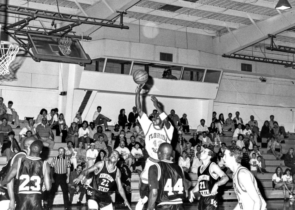 Florida Tech man shooting basketball in front of crowd surrounded by players from the other team