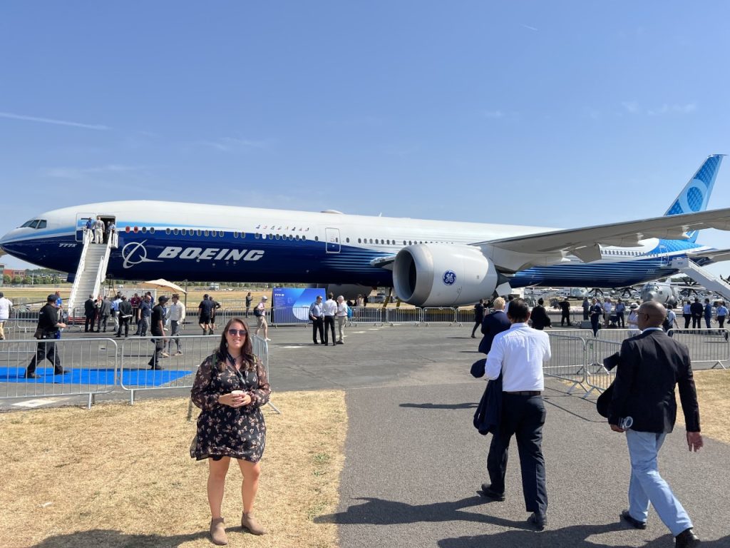 Taylor Rains '17 standing in front of the Boeing 777X test plane at the 2022 Farnborough International Air Show in England.
